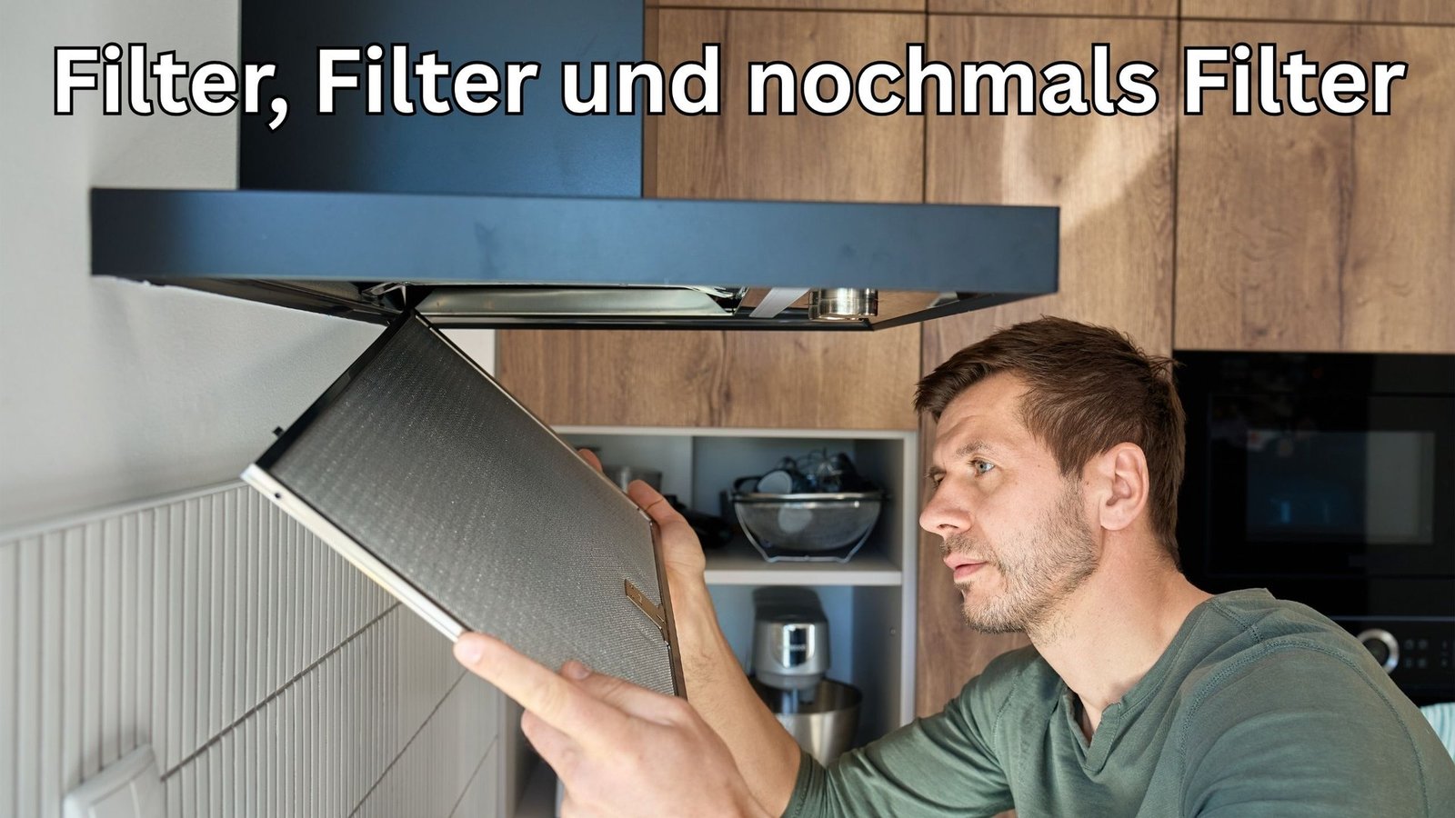 Ein Mann nimmt den Metallfettfilter aus einer Dunstabzugshaube in einer Küche